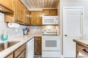 A kitchen with wooden cabinets, a microwave, a stove, and a sink. - Ski, Soak & Relax | Cozy Beech Mountain Condo (Beech Mountain)
