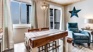 A dining area with a wooden table and chairs, a hanging light fixture, and a star decoration on the wall. - Ski, Soak & Relax | Cozy Beech Mountain Condo (Beech Mountain)