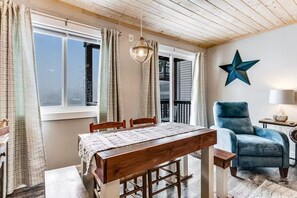 A dining area with a wooden table and chairs, a hanging light fixture, and a star decoration on the wall. - Ski, Soak & Relax | Cozy Beech Mountain Condo (Beech Mountain)