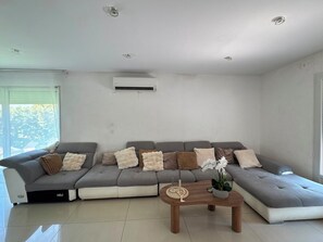 Een moderne woonkamer met een grijze modulaire bank, een houten salontafel en een potorkidee.