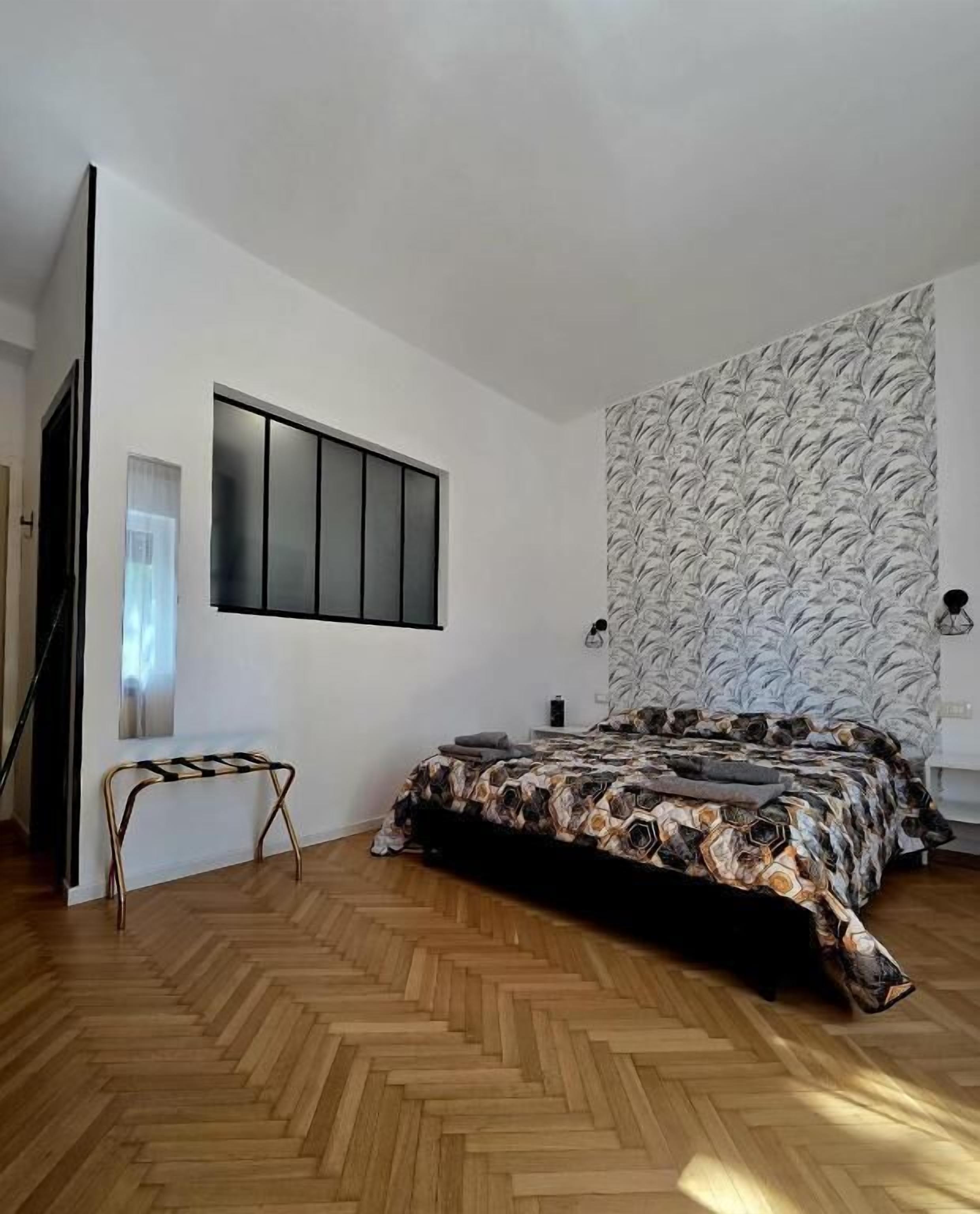 Una camera da letto con un letto, una panchina, una TV a muro e una parete decorata.