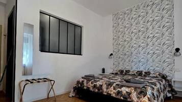 Una camera da letto con un letto, una panchina, una TV a muro e una parete decorata.