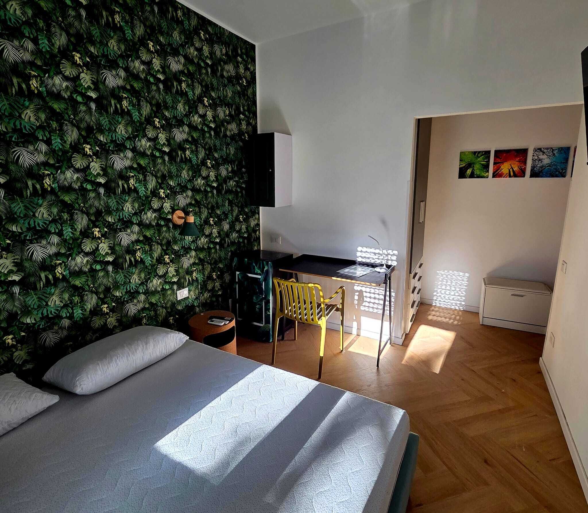 Una camera da letto con un letto, una scrivania e una parete ricoperta di vegetazione.