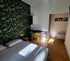 A bedroom with a bed, a desk, and a wall covered in foliage. - Elycon House Bergamo (Bergamo)