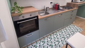 Una cocina moderna con armarios grises, horno empotrado, microondas y estufa a gas.