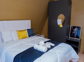 A neatly made bed with white bedding, a blue accent, and a pair of towels.