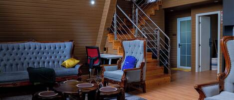 A spacious loft-style living area with a high ceiling, a staircase, and a view of the sky.