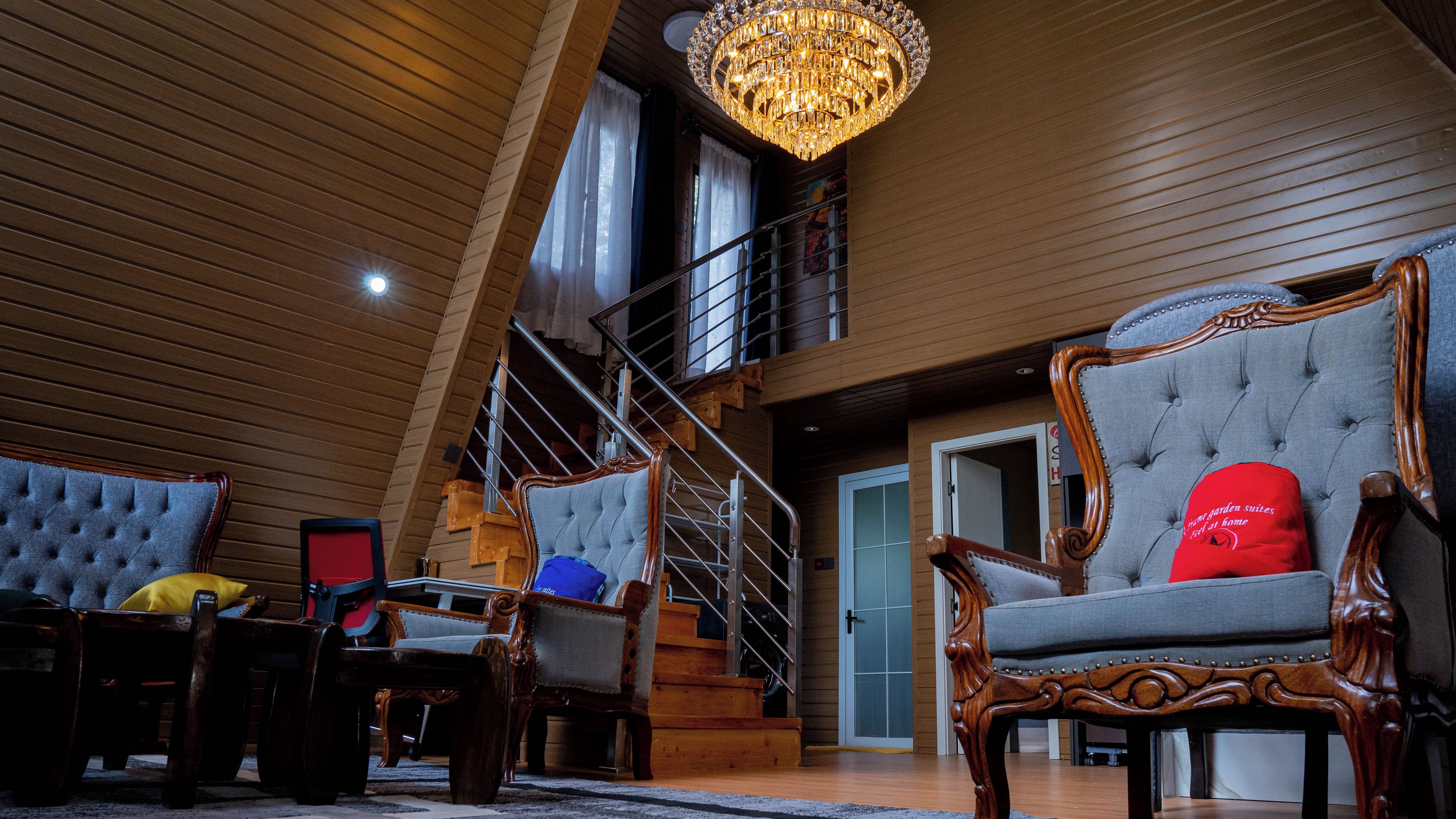 A spacious room with a grand staircase, elegant wooden furniture, and a chandelier.