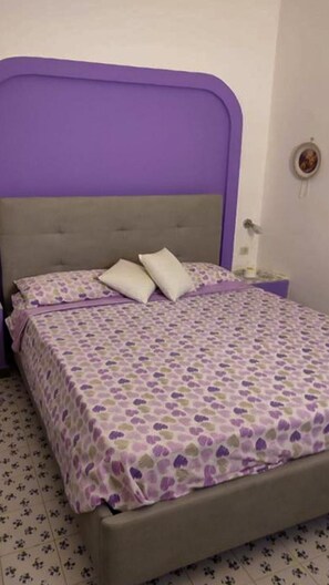 Ein Bett mit violettem Kopfteil und einem gemusterten Bettbezug.