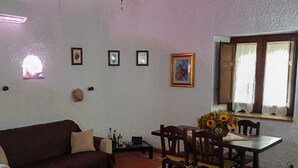 A living room with a sofa, dining table, chairs, and a rug. - Gisella's House Vacation Rental (Castellammare del Golfo)