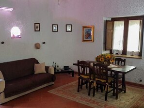 Ein Wohnzimmer mit einer Couch, einem Esstisch, Stühlen und einem Teppich.