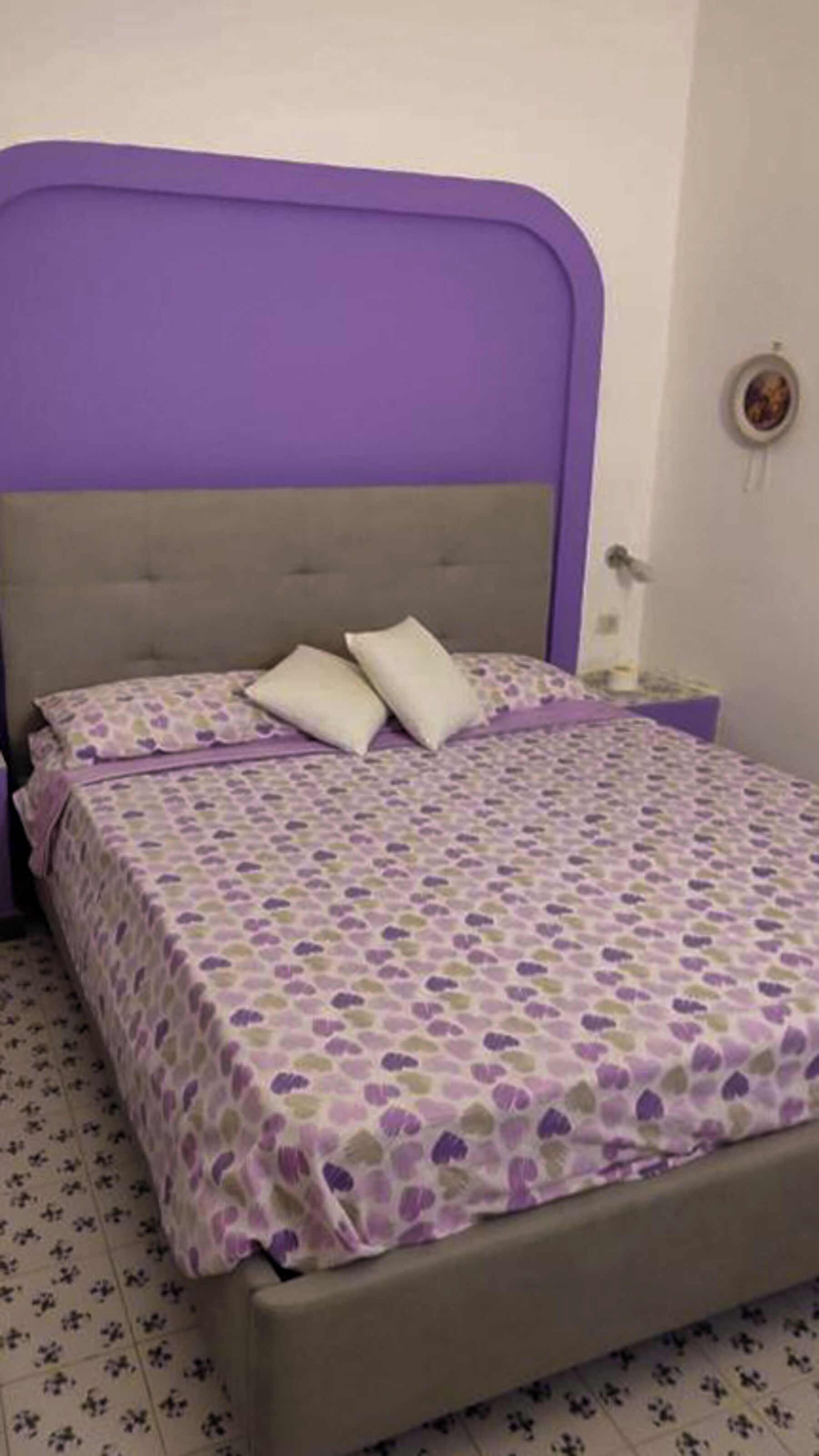 A bed with a purple headboard and a patterned bedspread.
