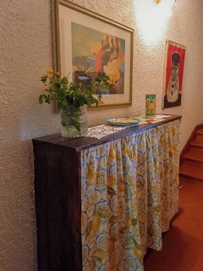 Ein Zimmer mit Holzschreibtisch, Blumen in einer Vase, einem gerahmten Gemälde und einer Treppe.
