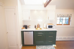 A kitchen with white cabinets, a white countertop, a microwave, a sink, and a refrigerator.