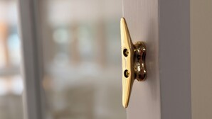 A close-up of a brass door latch on a white door.