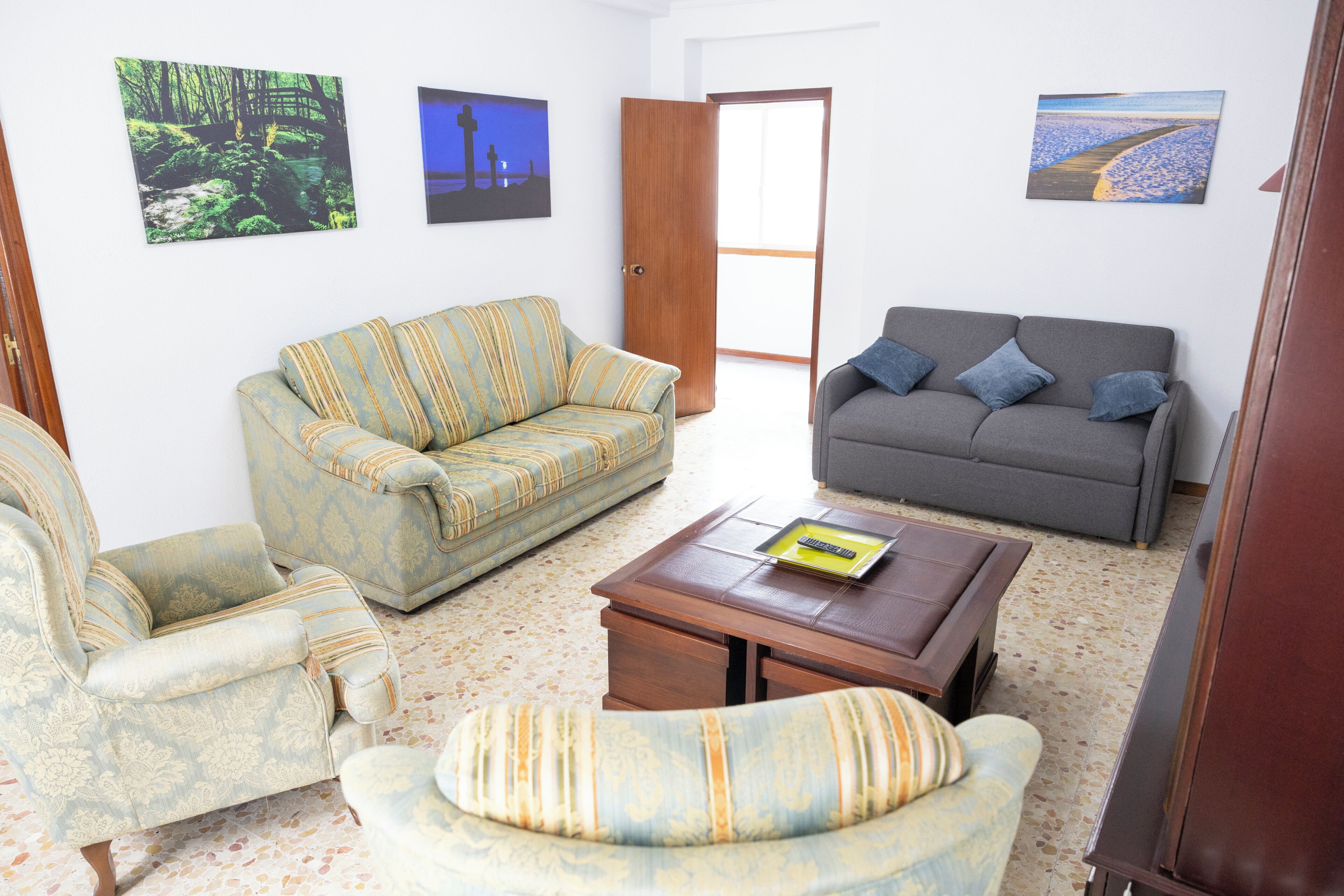 Una sala de estar con dos sofás, una mesa de centro y una puerta que da al exterior.