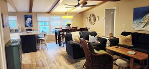 A living room with a fireplace, a dining area with a table and chairs, and a kitchen with a counter and cabinets.
