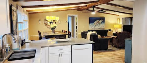 A kitchen with a dining area, a black sofa, and a painting of a sea turtle.