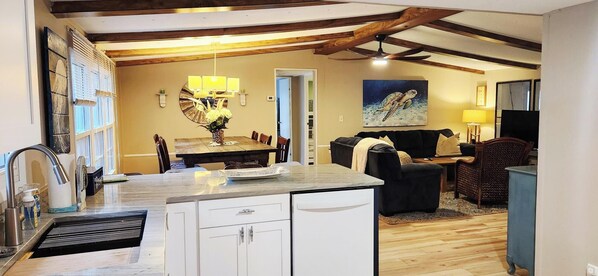 A kitchen with a dining area, a black sofa, and a painting of a sea turtle.