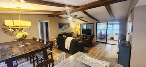 A spacious living area with a wooden dining table, a sofa, and a television.