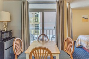 Ein Hotelzimmer mit Esstisch, Stühlen, einer Mikrowelle, einem Bett und Blick auf einen Balkon mit Sitzgelegenheiten.