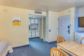 A compact hotel room with a kitchenette, a dining area with a table and chairs, and a single bed. - Ocean View Studio | Bay Watch Resort + Pools (North Myrtle Beach)