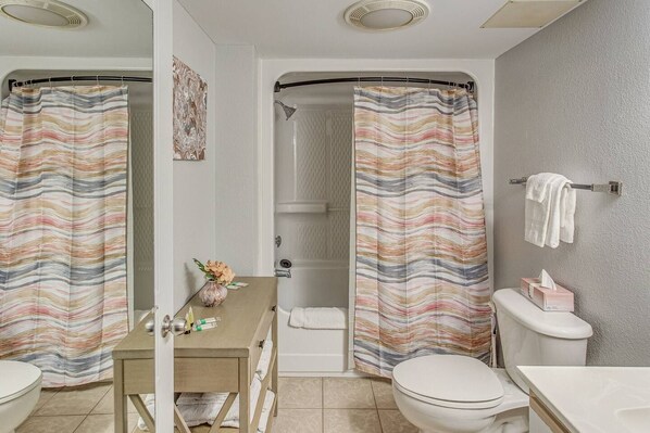 Un bagno con tenda da doccia, un water, un lavandino e un porta asciugamani.