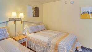 Ett hotellrum med en säng, sängbord, lampor och konstverk på väggarna.
