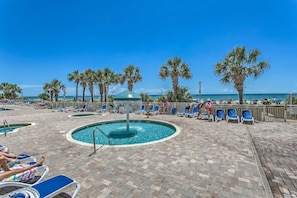 A pool area with lounge chairs and a central water feature. - Ocean View Studio | Bay Watch Resort + Pools (North Myrtle Beach)