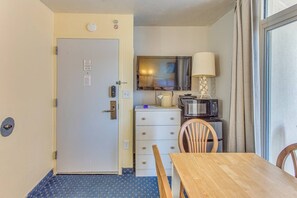 A compact room with a kitchenette, a dining table, and a door with a lock. - Seas the Day with Ocean Views & a Lazy River (North Myrtle Beach)