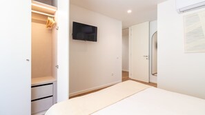 A bedroom with a bed, a television mounted on the wall, a wardrobe, and a door leading to another room. - Polacos Residence | 2BR | Apt J by LovelyStay (Vila Nova de Gaia)