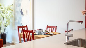 Eine moderne Küche mit Esstisch, Stühlen und einer Edelstahl-Spüle.