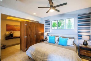 Une chambre à coucher comprenant un lit, une armoire, un ventilateur de plafond et des œuvres d’art mural.