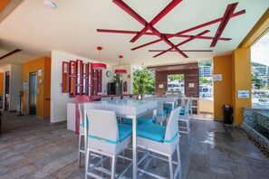 A modern outdoor dining area with white wicker furniture and blue cushions, a red ceiling design, and a view of the surrounding cityscape. - Amazing V177 Ocean Chic (Puerto Vallarta)