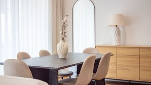 A dining area with a marble table, six chairs, a vase with dried flowers, a mirror, and a lamp on a wooden cabinet. - Polacos Residence | 2BR | Apt H by LovelyStay (Vila Nova de Gaia)