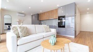 A modern living room with a white sofa, two round wooden tables, and a decorative vase. - Polacos Residence | 2BR | Apt H by LovelyStay (Vila Nova de Gaia)