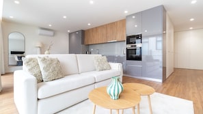 A modern living room with a white sofa, two round wooden tables, and a decorative vase. - Polacos Residence | 2BR | Apt H by LovelyStay (Vila Nova de Gaia)