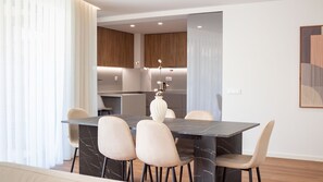 Un espace repas moderne avec une table en marbre, quatre chaises et un vase rempli de fleurs.