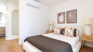 A bedroom with a bed, two bedside tables, a wall-mounted air conditioner, and two framed artworks. - Polacos Residence | 2BR | Apt K by LovelyStay (Vila Nova de Gaia)