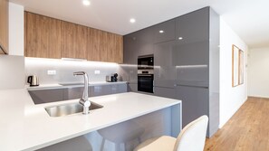 A modern kitchen with a built-in oven, a coffee machine, and a stainless steel sink. - Polacos Residence | 2BR | Apt S by LovelyStay (Vila Nova de Gaia)