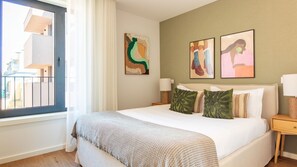 A hotel room with a large bed, two bedside tables, a window with curtains, and artwork on the walls. - Polacos Residence | 2BR | Apt S by LovelyStay (Vila Nova de Gaia)
