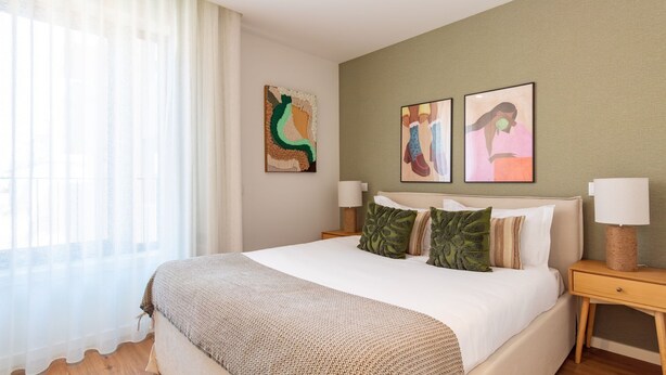 A hotel room with a bed, two bedside tables, a window with sheer curtains, and two wall-mounted artworks. - Polacos Residence | 2BR | Apt S by LovelyStay (Vila Nova de Gaia)