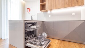 A modern kitchen with a dishwasher, wooden cabinets, and a fire extinguisher on the wall. - Polacos Residence | 2BR | Apt S by LovelyStay (Vila Nova de Gaia)