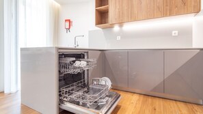 A modern kitchen with a dishwasher, wooden cabinets, and a fire extinguisher on the wall. - Polacos Residence | 2BR | Apt S by LovelyStay (Vila Nova de Gaia)
