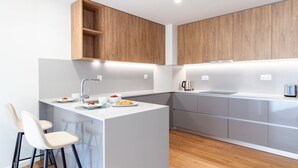 A modern kitchen with white countertops, wooden cabinets, and a central island with bar stools. - Polacos Residence | 2BR | Apt S by LovelyStay (Vila Nova de Gaia)