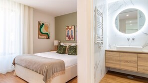 Una habitación de hotel con cama, baño con lavamanos de mármol y obras de arte en las paredes.