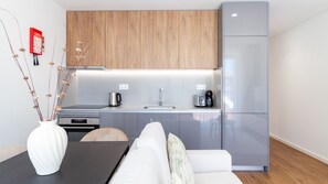 Una cocina moderna con horno empotrado, lavamanos y refrigerador. Hay un comedor con una mesa y sillas.