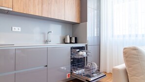 Ett modernt kök med gråa skåp, en inbyggd diskmaskin och en kaffebryggare.