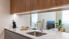 Eine moderne Küche mit integriertem Spülbecken, einer Kaffeemaschine und einem Essbereich mit Tisch für zwei Personen.