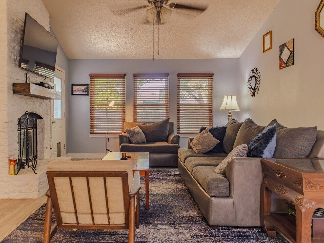 A living room with a fireplace, a sofa set, a coffee table, and a television mounted on the wall.